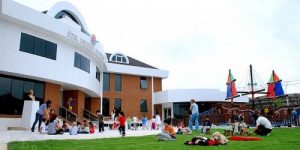 Özel bir anaokulunun bahçesinde çocuklar oyun oynuyor, öğretmenler gözetim yapıyor. Rainwater Rainbow